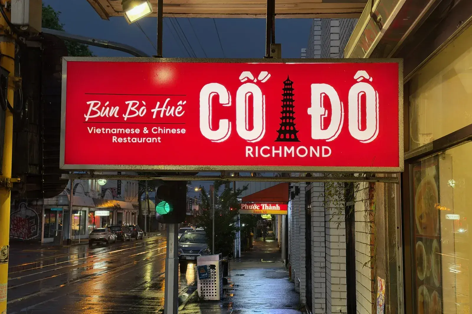 ป้ายไฟสีแดงของร้านอาหารเวียดนามบนถนน Victoria Street ริชมอนด์ เขียนคำว่า Bún Bò Huế ตอนหัวค่ำหลังฝนตก