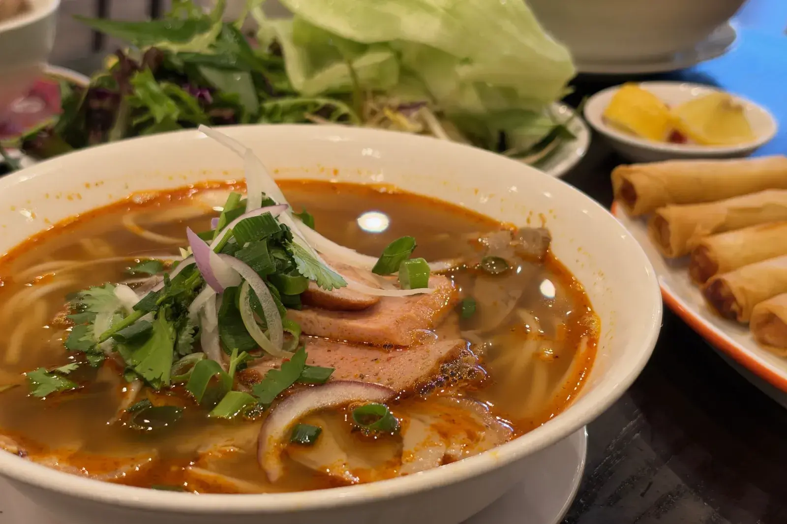 บุ๋นบ่อเว้ ก๋วยเตี๋ยวเนื้อรสจัดเวียดนาม น้ำซุปสีแดงส้ม ใส่เนื้อสไลซ์ หมูยอเวียดนาม และผักหอม