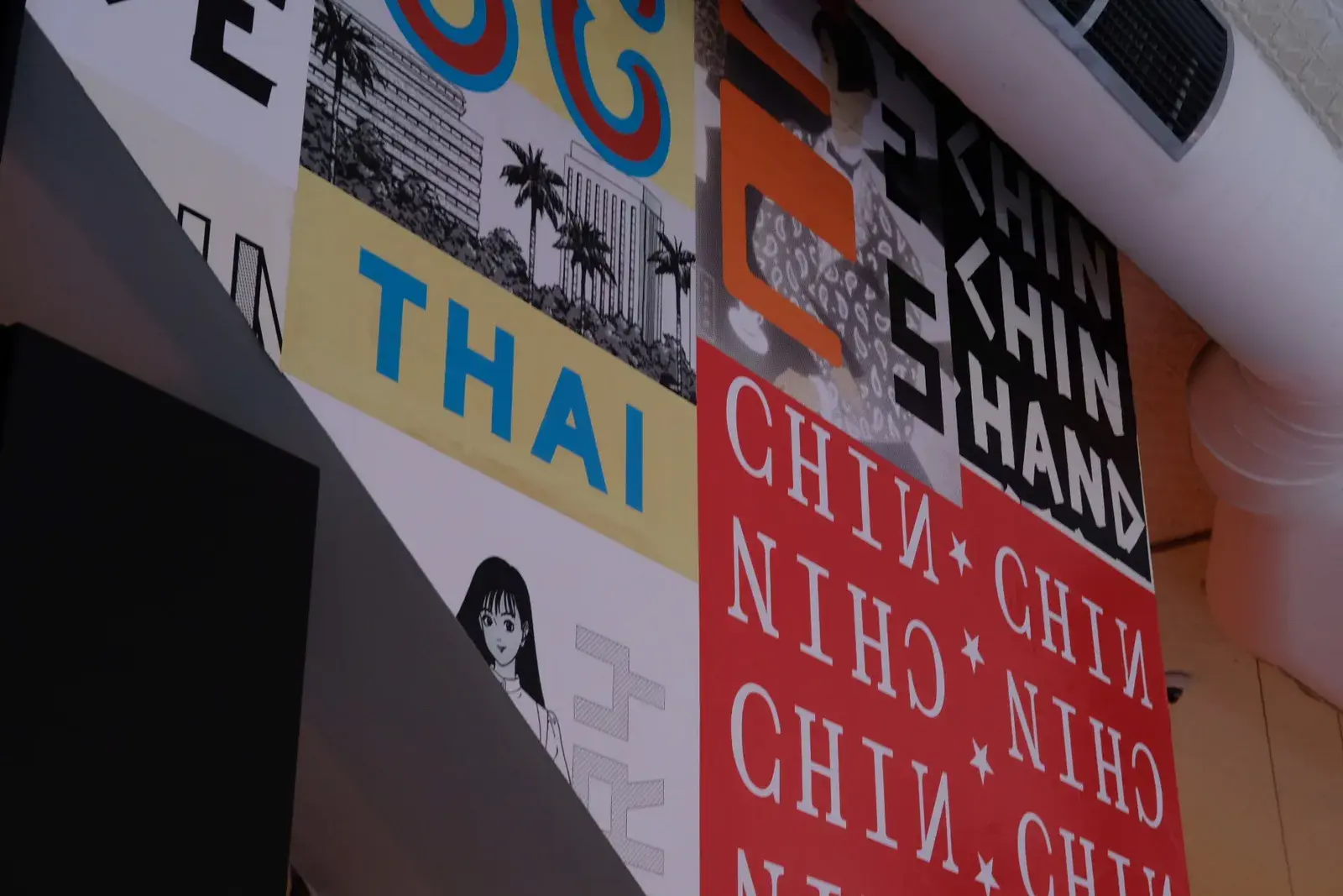 ป้ายผนังร้านอาหารมีคำว่า THAI และ CHIN CHIN ตัวอักษรหลายภาษาสีแดง เหลือง ดำ